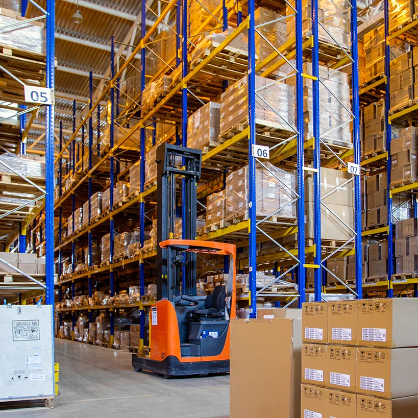 Forklift moving palletized inventory down a warehouse aisle