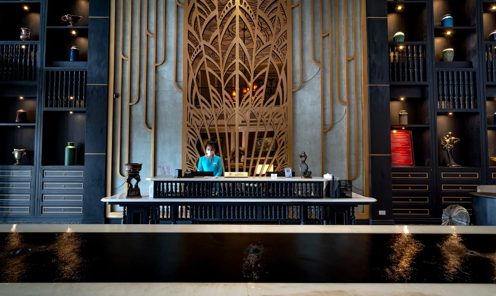 Receptionist standing behind the front desk in a clean, modern hotel lobby