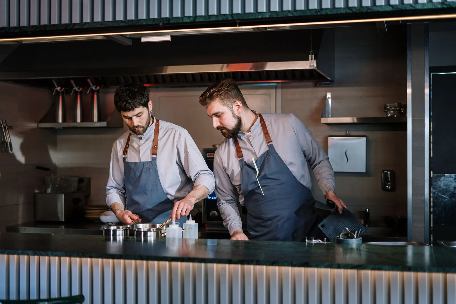 Two chefs plating dishes in a clean, modern restaurant kitchen