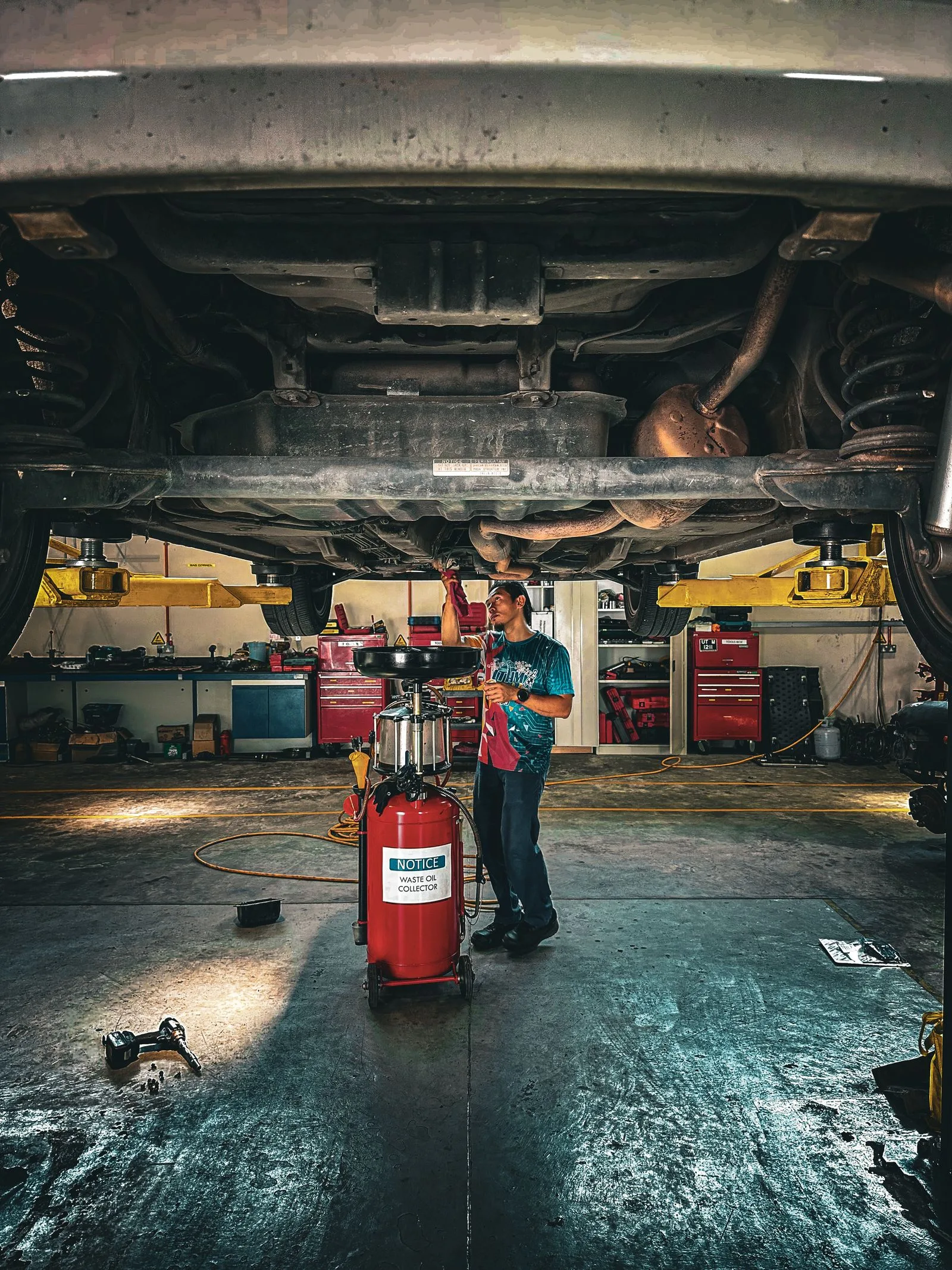 Auto mechanic working under a vehicle on a hydraulic lift in a professional repair shop